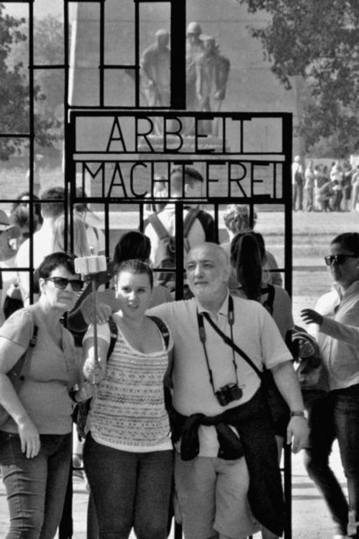 Besucher stehen vor dem Tor mit der Aufschrift „Arbeit macht frei“ in einem Konzentrationslager.