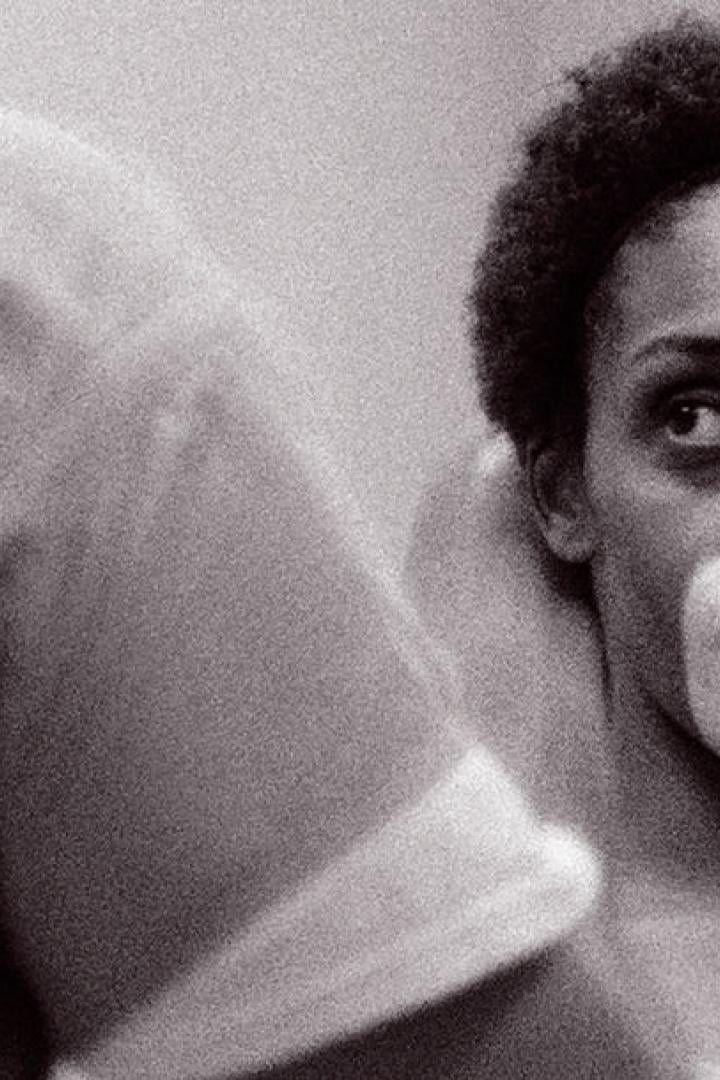 Eine Frau mit kurzen, lockigen Haaren schaut über ihre Schulter.