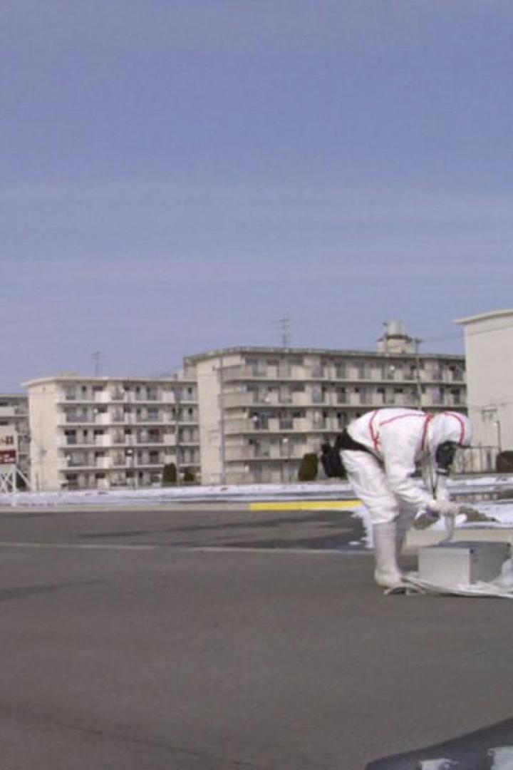 Zwei Personen in Schutzanzügen arbeiten in einem städtischen Gebiet mit wenig Schnee.
