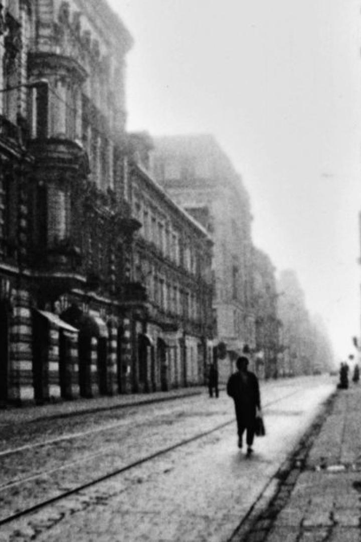 Eine belebte Straße in einer europäischen Stadt mit Menschen und Straßenbahnschienen.