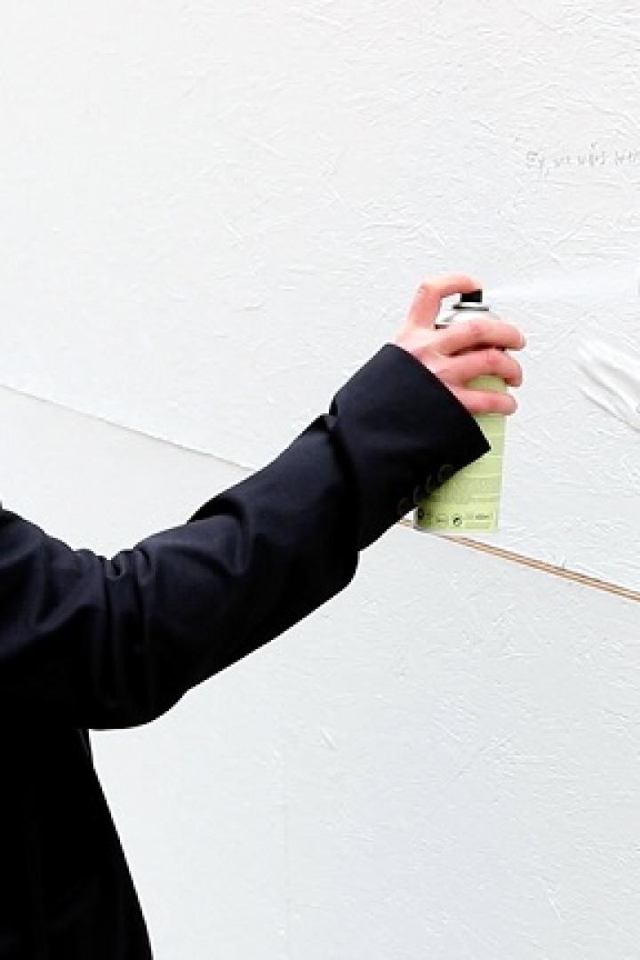 Eine Frau sprüht Graffiti auf eine weiße Wand.