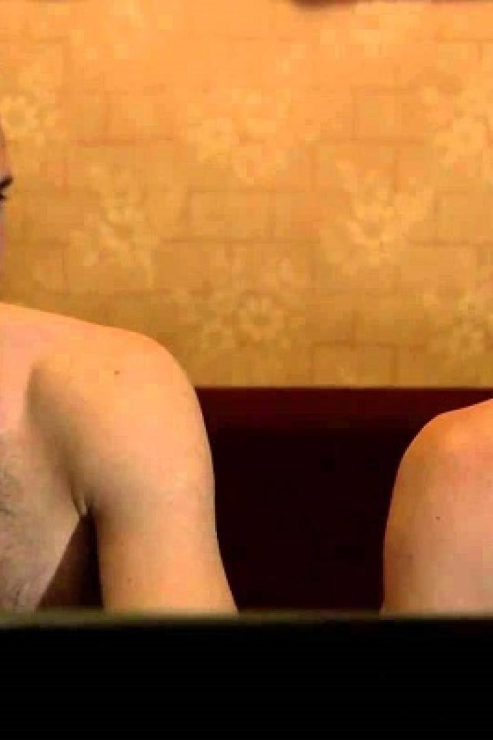 Zwei Männer sitzen mit freiem Oberkörper vor einem Laptop.