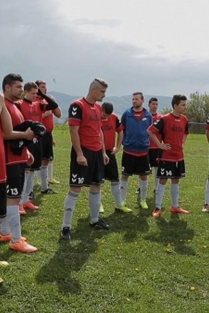 Ein Fußballtrainer bespricht eine Taktik mit seiner Mannschaft auf dem Spielfeld.