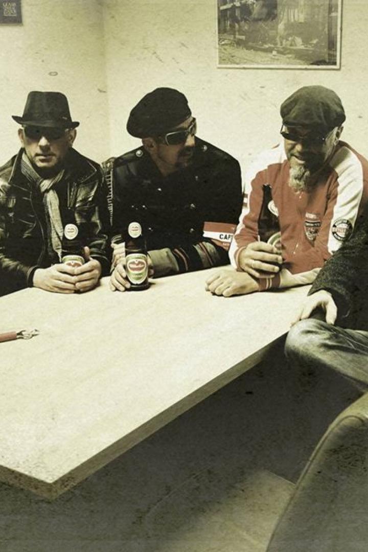 Eine Gruppe von sechs Männern sitzt an einem Tisch und trinkt Bier.