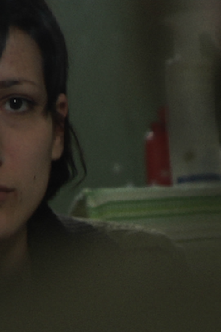 Eine Frau mit dunklen Haaren schaut aufmerksam in Richtung des Betrachters.