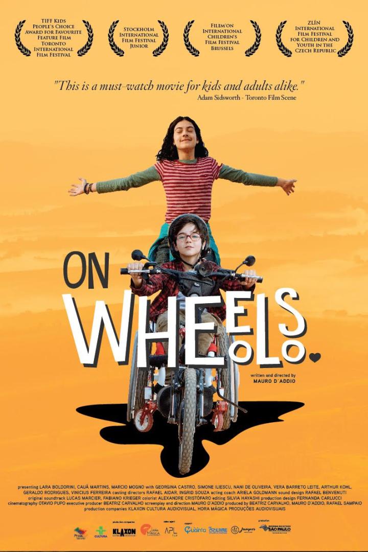 Ein Junge im Rollstuhl fährt ein Motorrad, während ein Mädchen hinter ihm steht, Filmposter „On Wheels“.