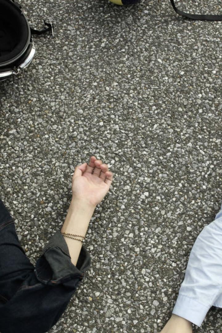 Ein junges Paar liegt auf dem Asphalt, ein Motorradhelm daneben.