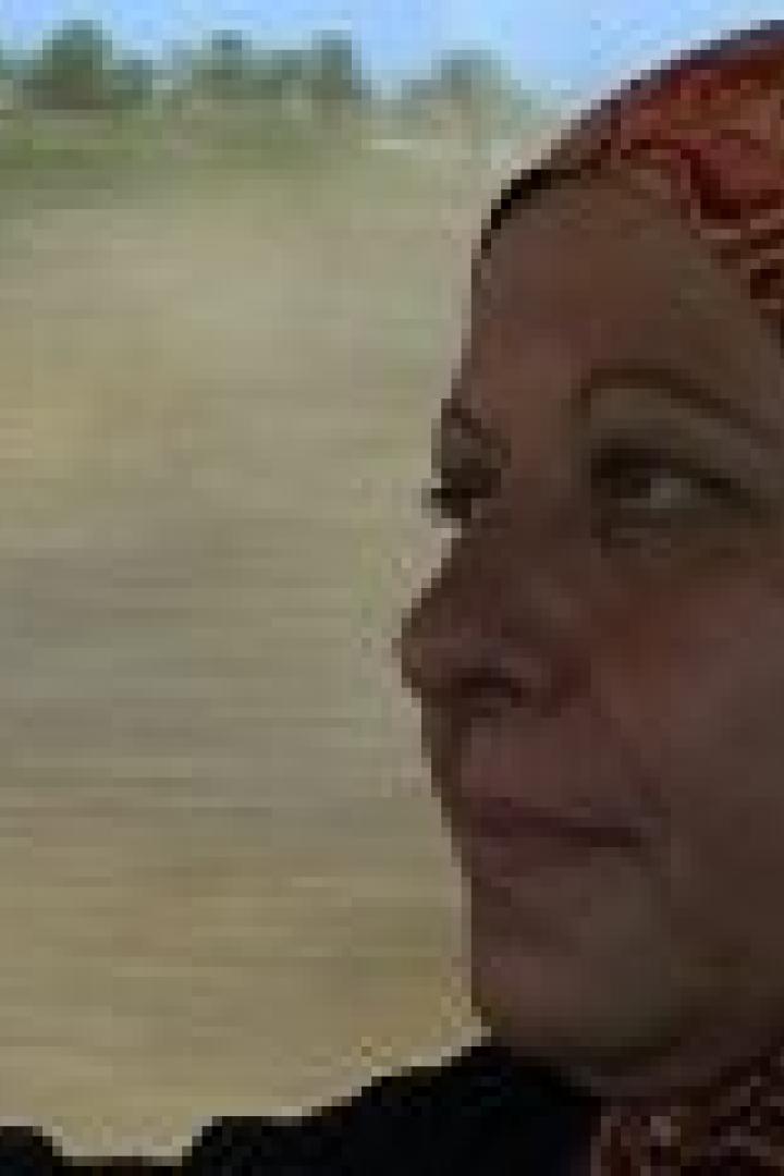 Eine Frau mit Kopftuch schaut aus dem Fenster eines fahrenden Fahrzeugs.