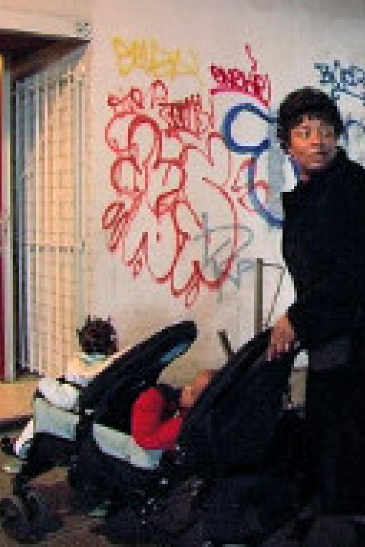 Eine Frau schiebt einen Kinderwagen vor einer Wand mit Graffiti.