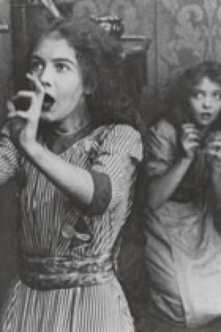 Zwei junge Frauen, eine mit einem Rohrlauscher, wirken erschrocken.