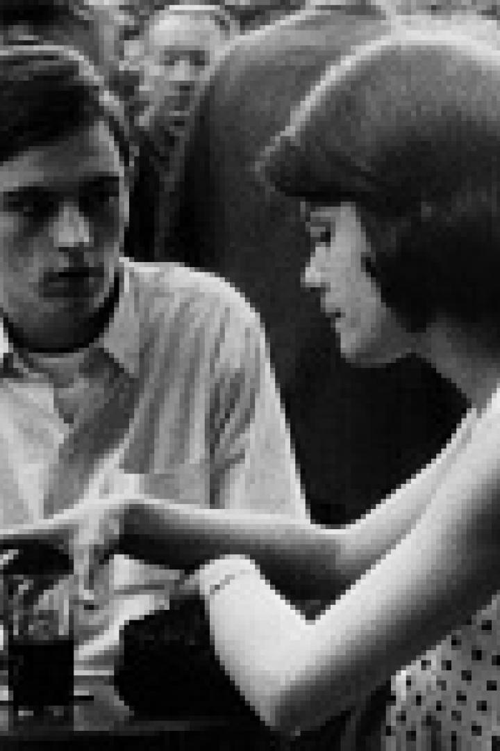 Ein junges Paar sitzt an einem Tisch im Freien und unterhält sich.