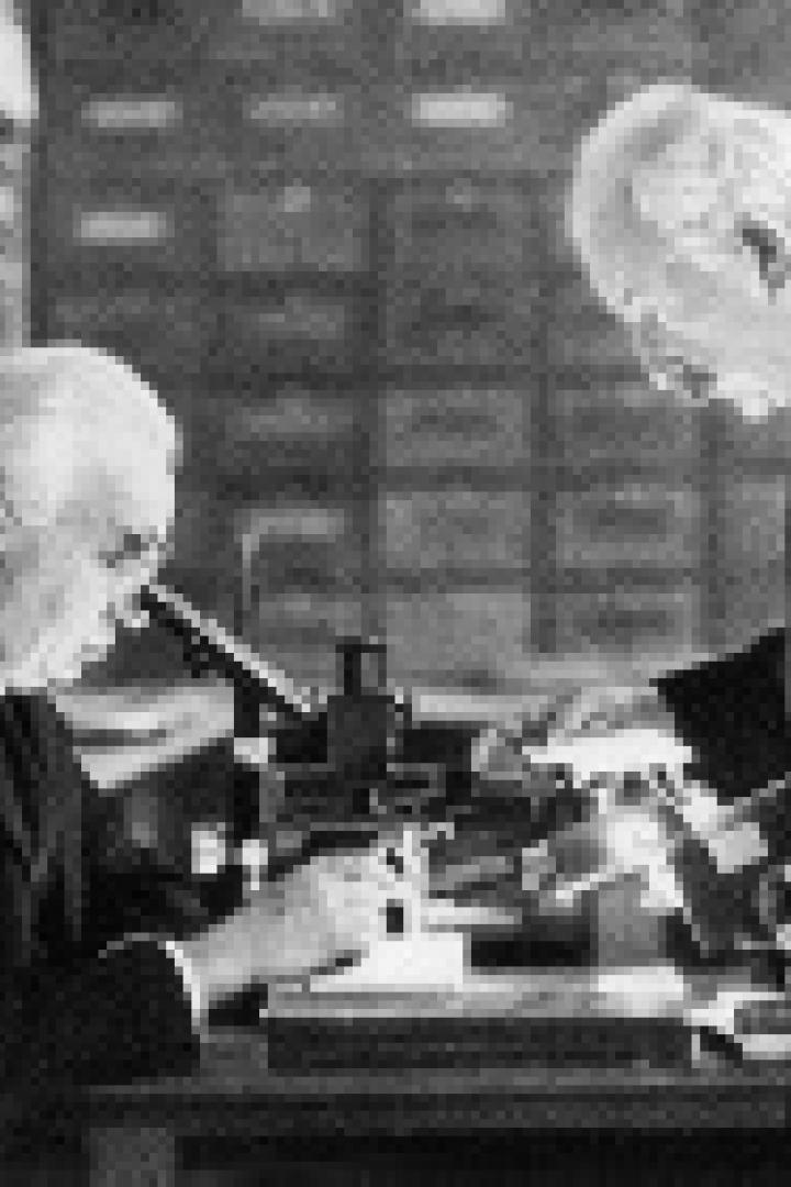 Zwei ältere Männer beugen sich über ein Mikroskop in einem Labor.