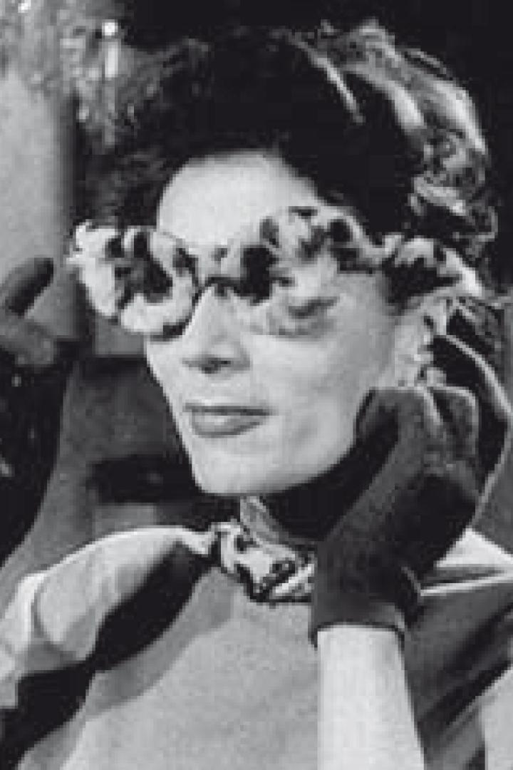 Eine Frau mit Handschuhen und einer ungewöhnlichen Brille posiert.