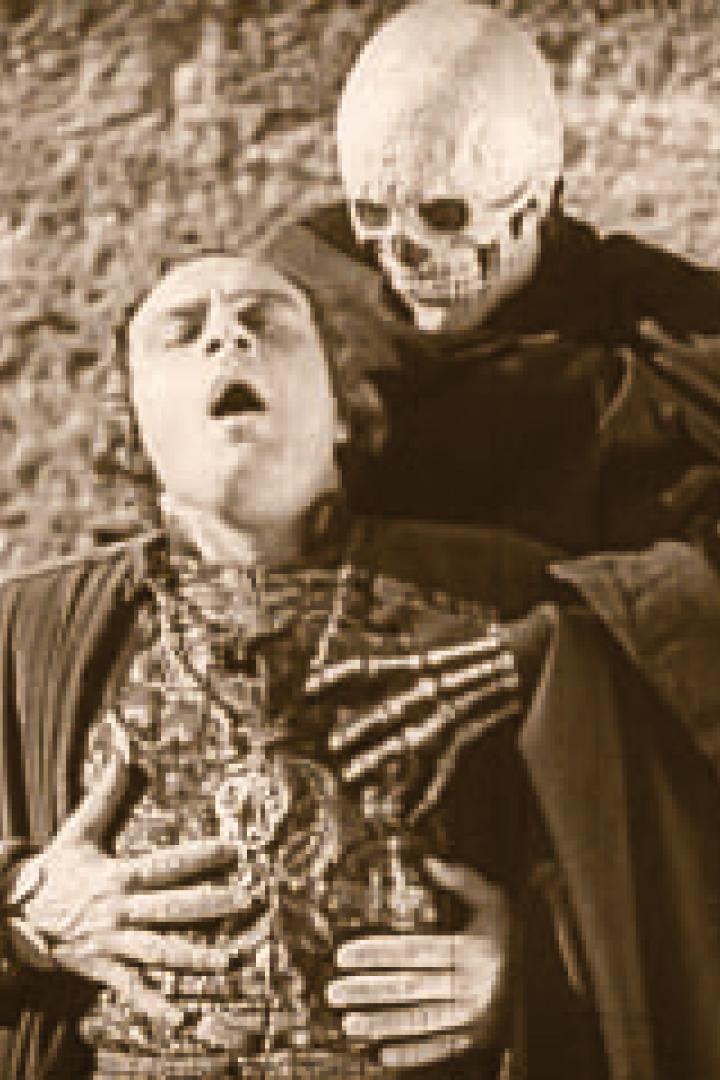 Ein Mann wird von einem Skelett mit Umhang umarmt.