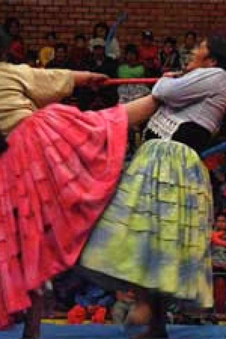 Zwei cholita-Wrestlerinnen kämpfen in traditioneller Kleidung in einem Ring.
