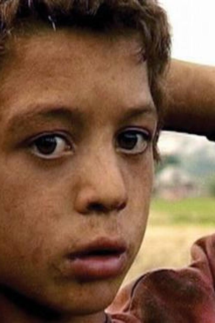 Ein junger, nachdenklicher Junge mit den Händen hinter dem Kopf.