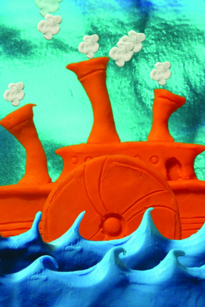 Ein orangefarbenes Raddampfer-Modell aus Knete auf blauem, gewelltem Untergrund.