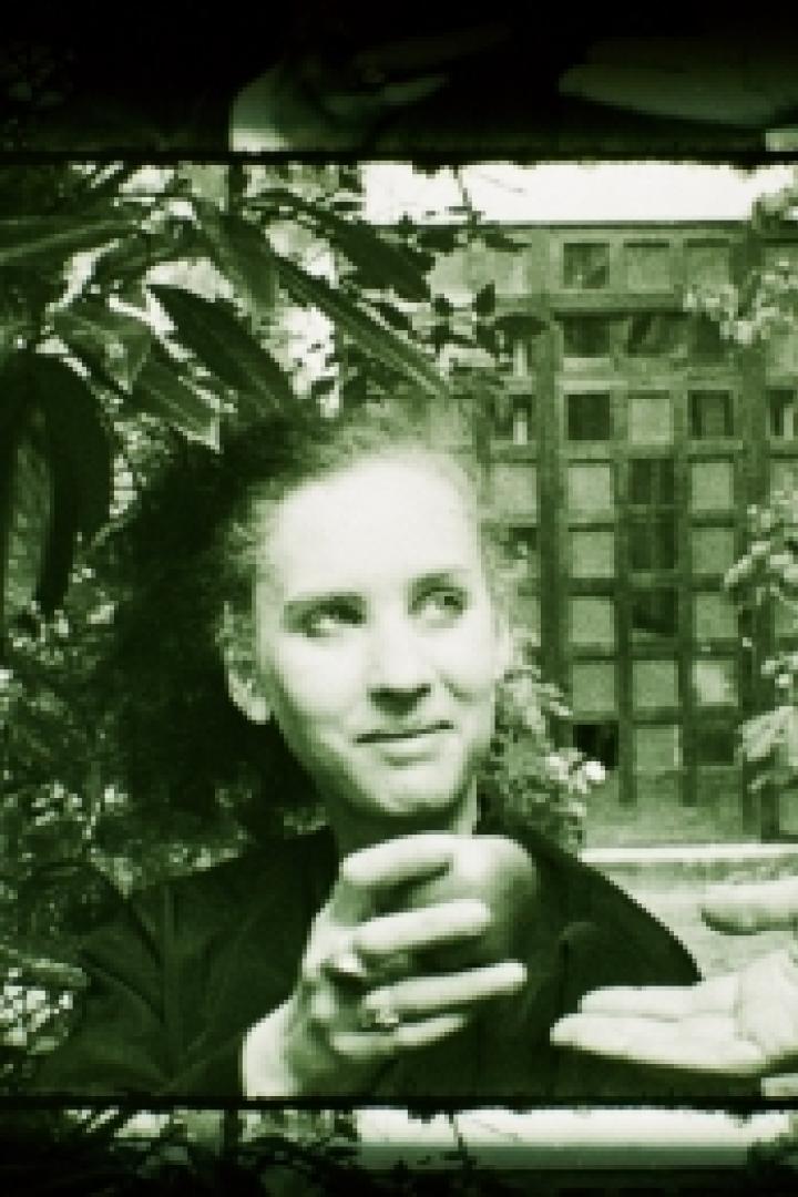Eine Frau hält einen Apfel in der Hand, der ihr von einer anderen Person gereicht wird.
