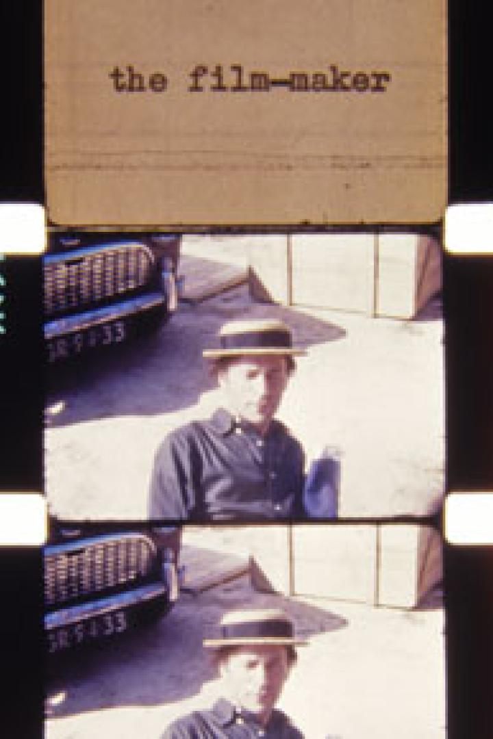 Ein Mann mit Hut steht vor einem Auto, aufgenommen auf einem Filmstreifen.