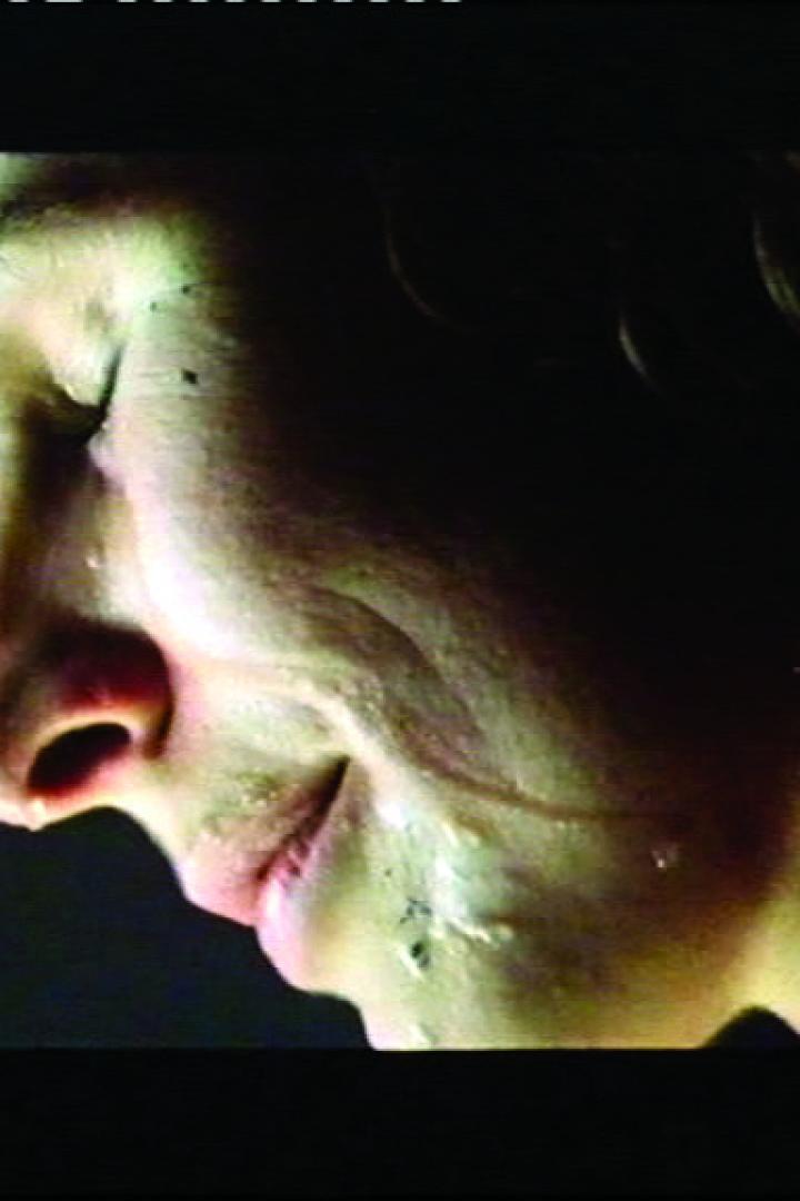 Nahaufnahme einer Frau mit geschlossenen Augen und Tränen im Gesicht.