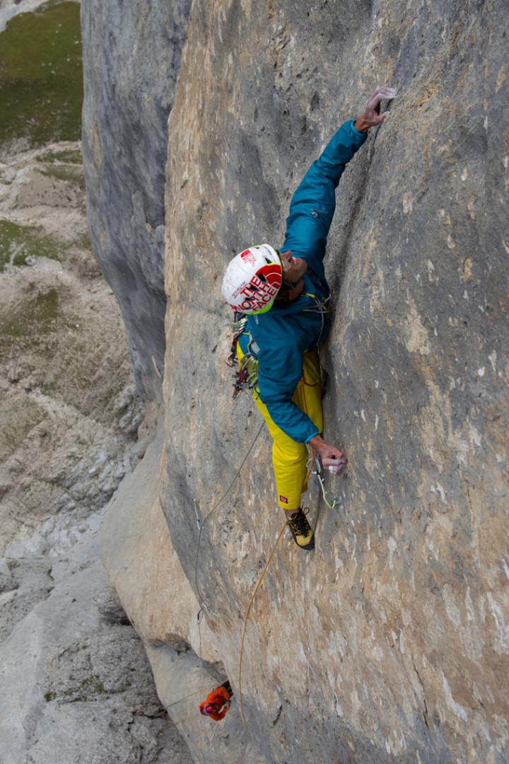 Ein Kletterer hängt an einer steilen Felswand, gesichert durch ein Seil.