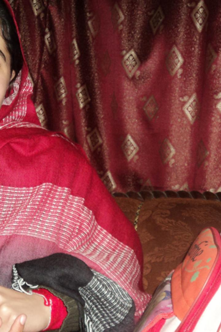 Malala Yousafzai lächelt mit einem roten und schwarzen Schal in die Kamera.