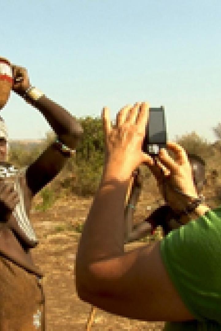 Eine Touristin fotografiert eine Frau vom Stamm der Mursi mit Lippenteller in Äthiopien.