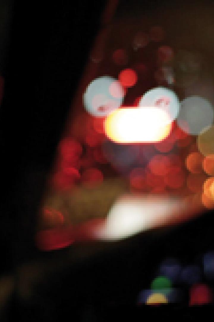 Eine Person fährt nachts Auto, mit verschwommenen Lichtern im Hintergrund.