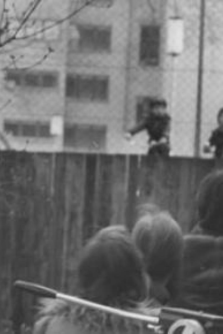 Eine Gruppe von Menschen beobachtet Kinder, die auf einer Mauer spielen.