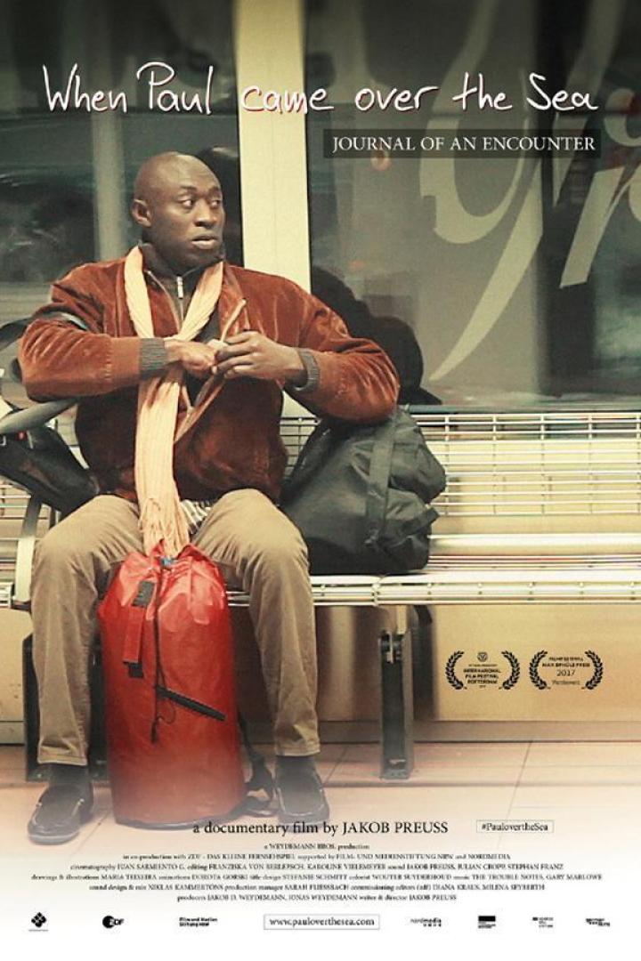 Ein Mann sitzt auf einer Bank mit einer roten Tasche, Plakat für den Film „When Paul came over the Sea“.