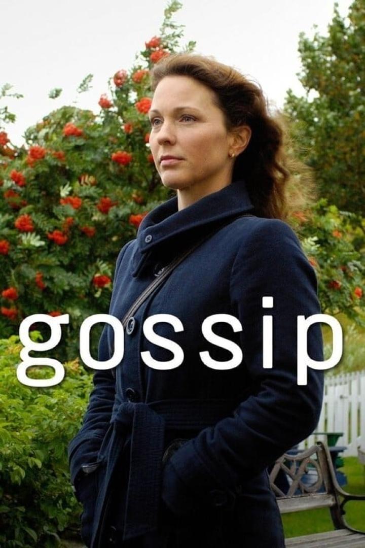 Eine Frau in einem Mantel steht vor einem Strauch mit roten Beeren.