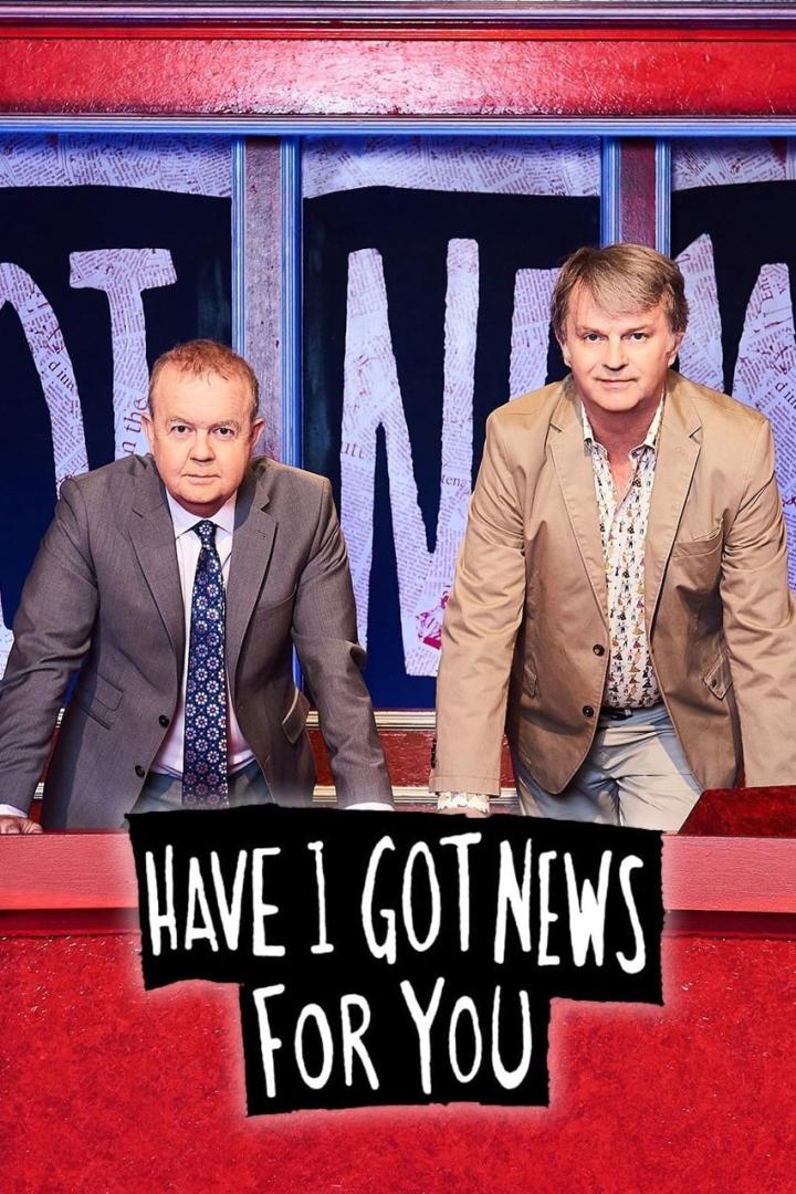 Zwei Männer stehen hinter einem Schreibtisch vor dem Hintergrund der Sendung „Have I Got News For You“.