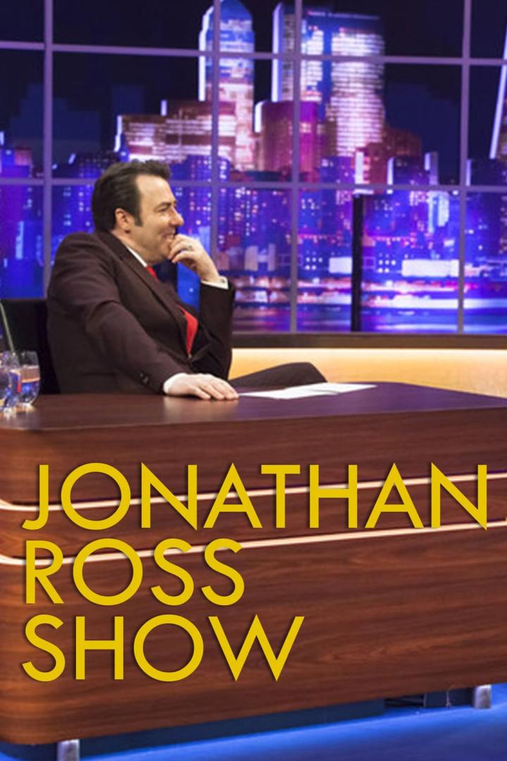 Jonathan Ross sitzt in seinem Studio vor einer beleuchteten Stadtkulisse.