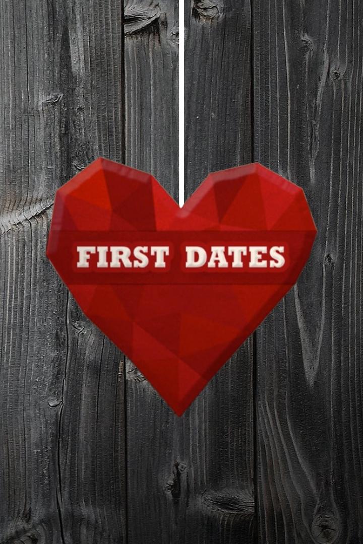 Ein rotes Herz mit der Aufschrift „First Dates“ hängt vor einer dunklen Holzwand.