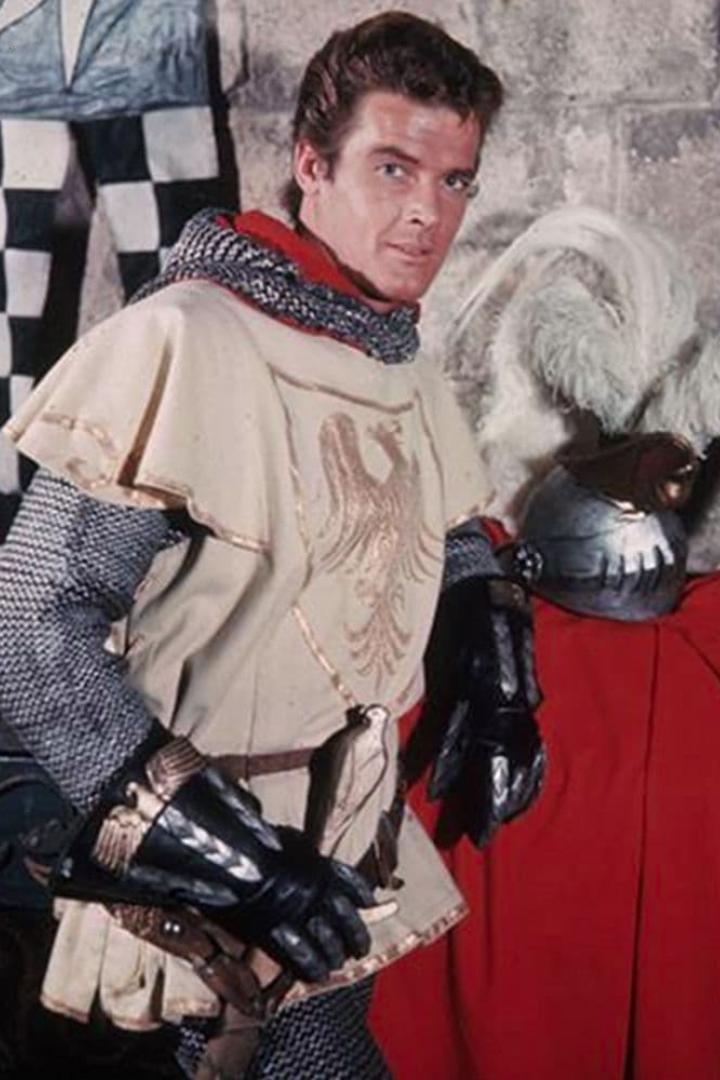 Ein Mann in Ritterrüstung posiert vor einem roten Vorhang.