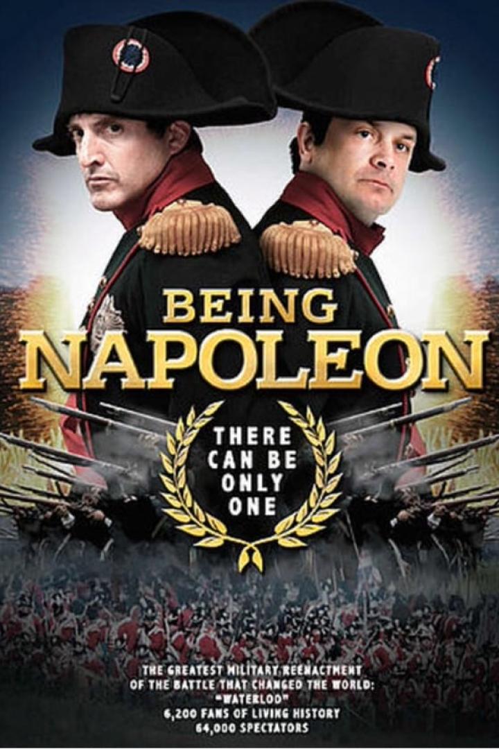 Das Filmplakat zu „Being Napoleon“ zeigt zwei Männer in Napoleon-Kostümen vor einer Schlachtfeld-Szene.