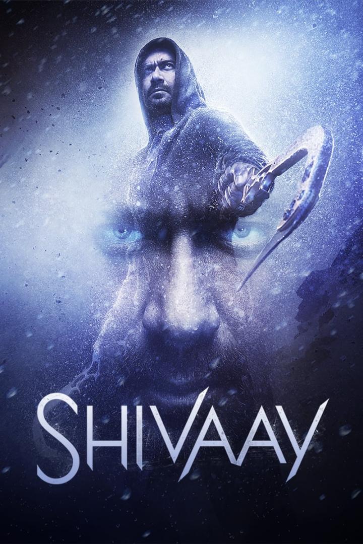 Das Filmplakat für „Shivaay“ zeigt einen Mann mit Kapuze und einer Waffe vor einem Gesicht im Hintergrund.