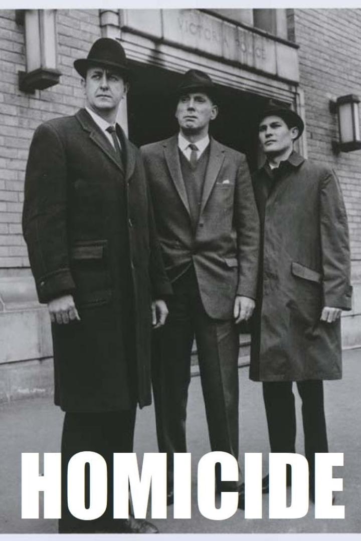 Drei Männer in Hüten und Mänteln stehen vor einem Gebäude der Victoria Police.