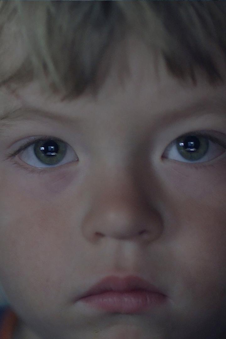 Nahaufnahme des Gesichts eines Kindes mit hellen Haaren und grünen Augen.