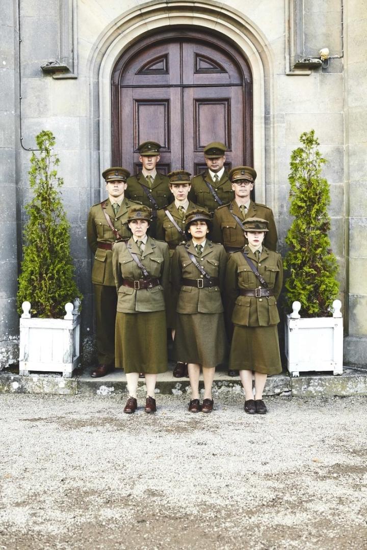 Eine Gruppe von Männern und Frauen in Uniformen posiert vor einer Tür.