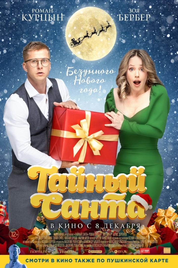 Das Filmplakat für „Tainy Santa“ zeigt Roman Kurtsyn und Zoya Berber mit einem großen, roten Geschenk vor einem Mond mit Weihnachtsmann.