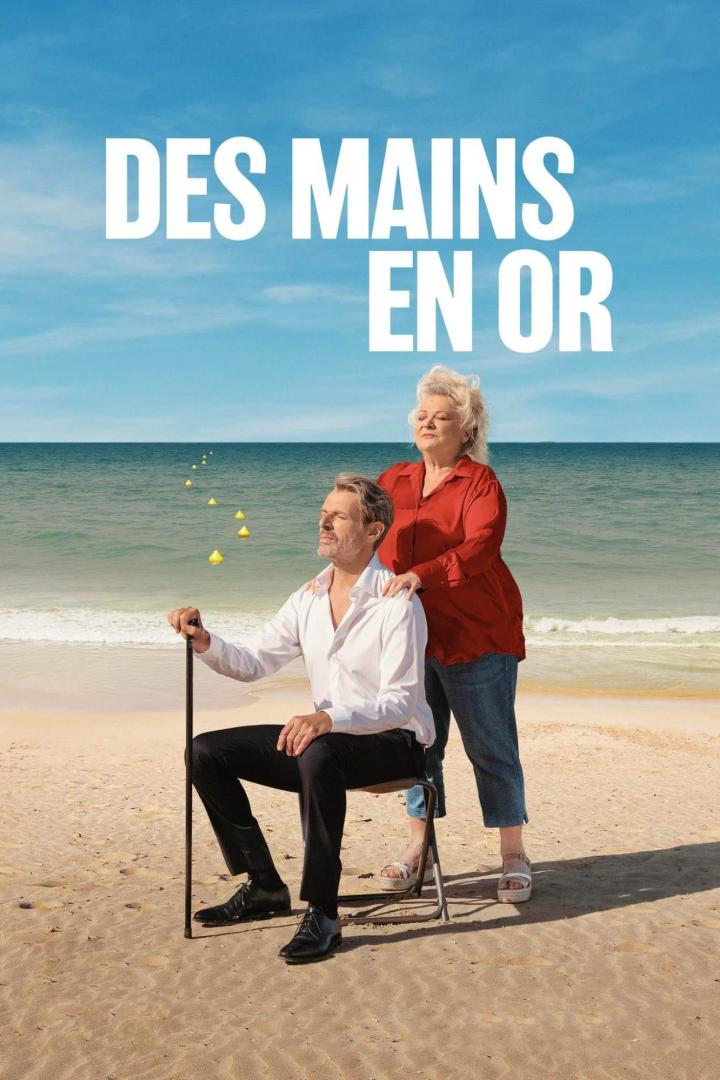 Ein Mann sitzt mit einem Stock am Strand, während eine Frau hinter ihm steht.