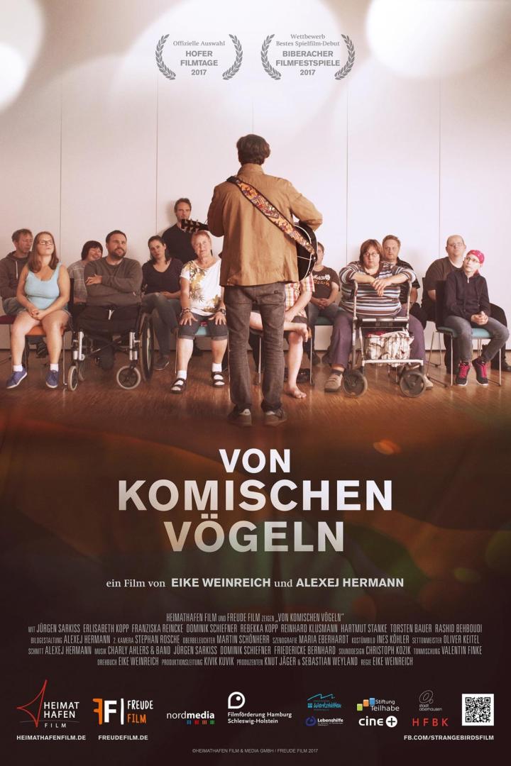 Ein Mann mit Gitarre steht vor einer Gruppe sitzender Menschen, Plakat für den Film „Von komischen Vögeln“.