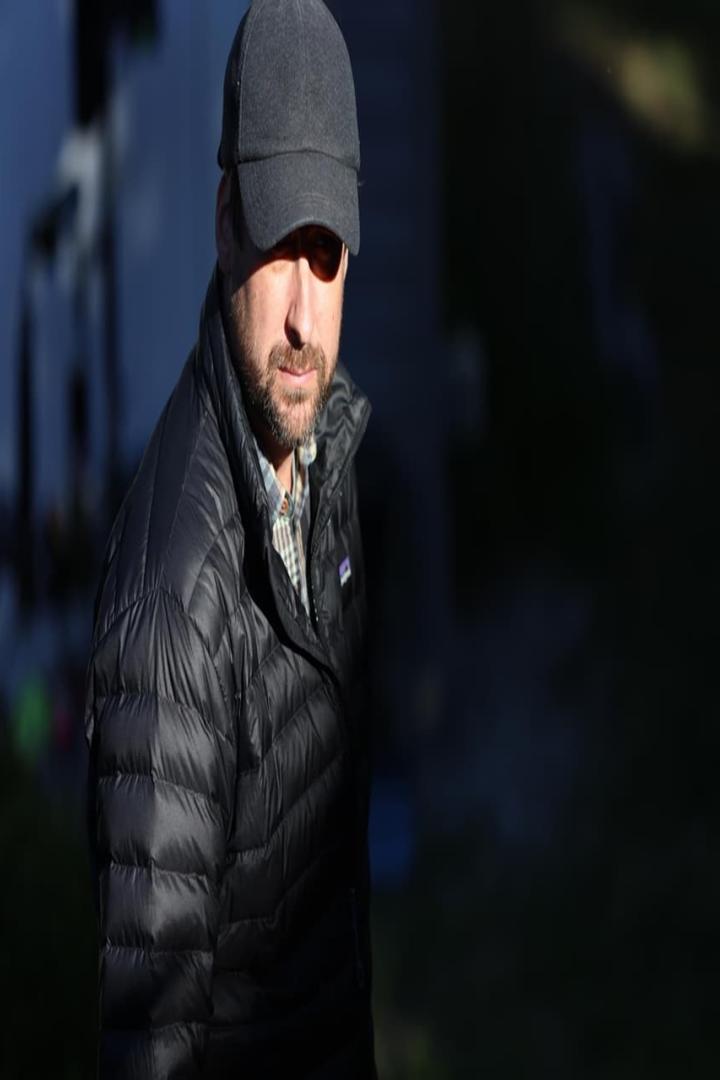 Ein Mann mit Bart und Mütze trägt eine schwarze Daunenjacke.