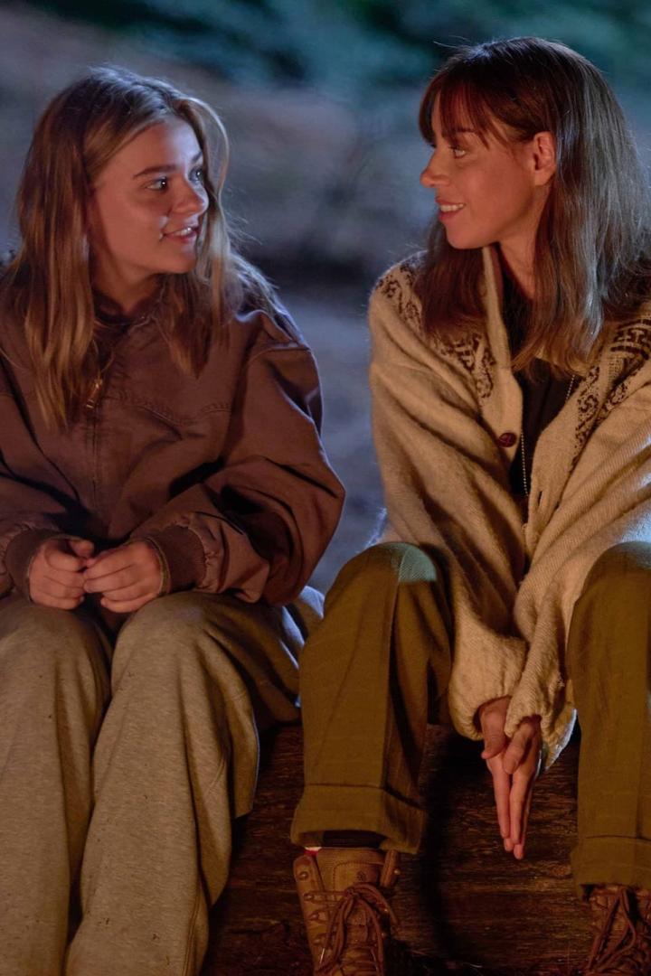 Zwei junge Frauen sitzen nebeneinander und schauen sich an.