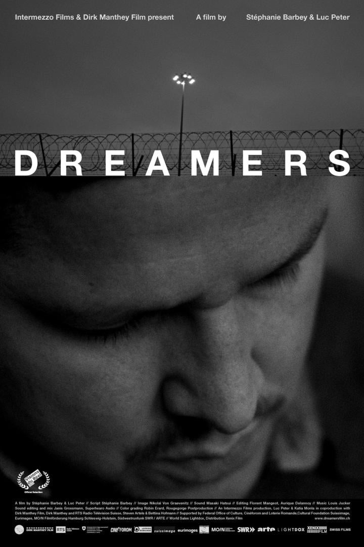 Das Filmplakat für „Dreamers“ zeigt einen Mann vor einem Zaun mit Stacheldraht.