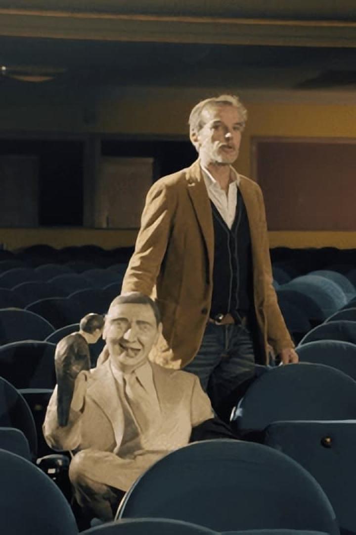 Ein Mann steht in einem leeren Theatersaal hinter einer Pappfigur von Groucho Marx.