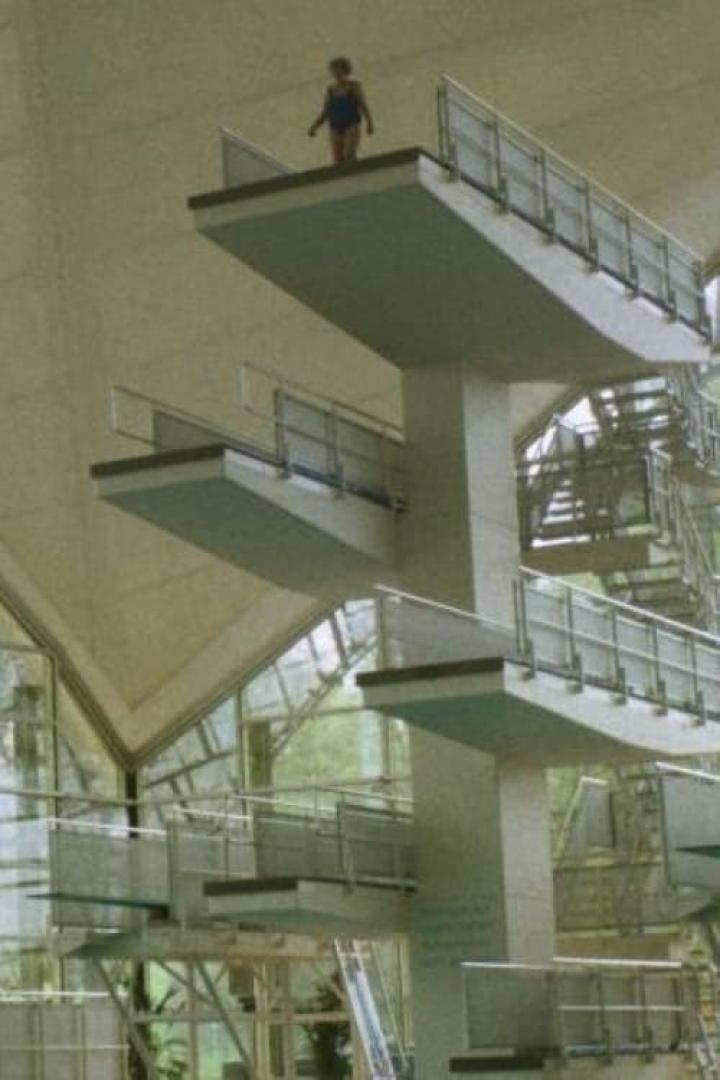 Ein Mädchen steht auf dem höchsten Sprungturm in einem Schwimmbad.