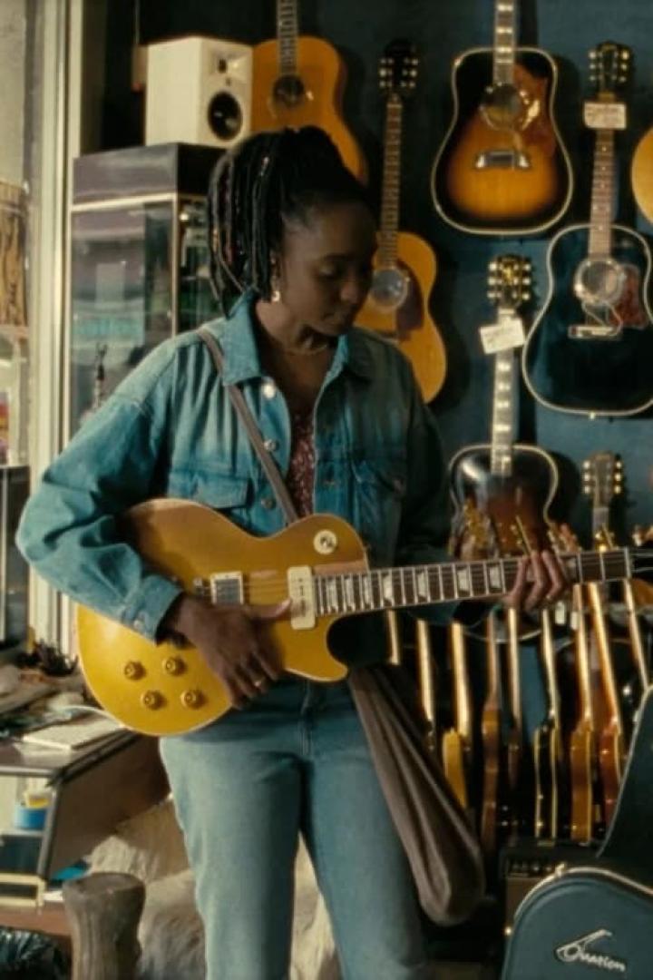 Eine junge Frau spielt in einem Musikgeschäft auf einer gelben E-Gitarre.