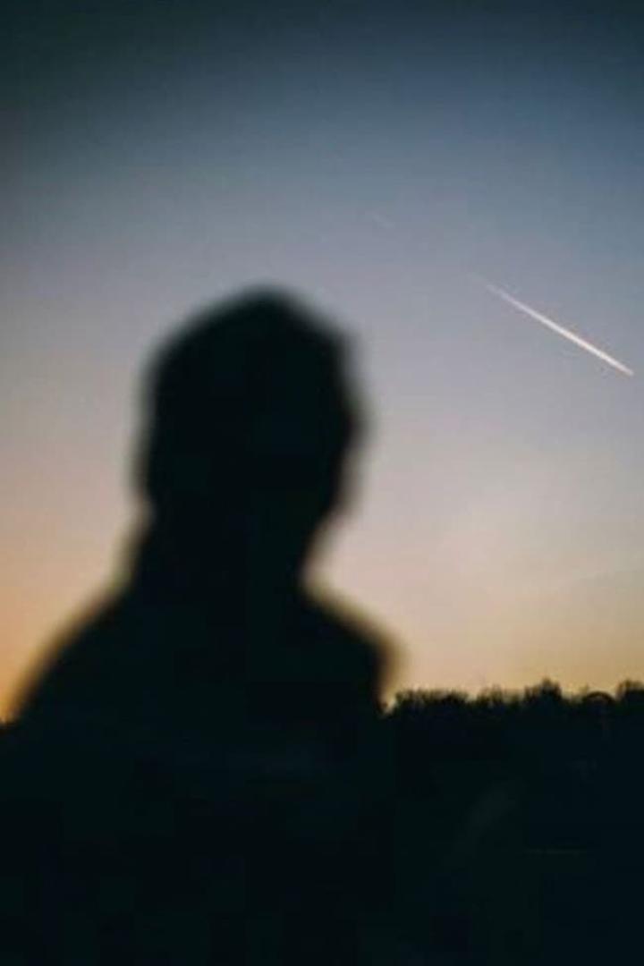 Die Silhouette einer Person vor einem Himmel mit einer Sternschnuppe.